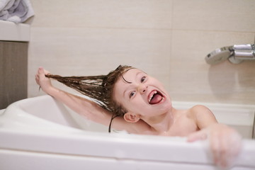 little girl in bath playing with soap foam