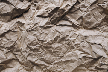 Background from very crumpled light brown wrapping vintage paper. The texture of cardboard made from recycled materials.