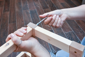 woman hands assembling wooden furniture with tools during quarantine isolation.