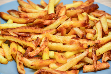 closeup french fries on a blue plate on a wooden background