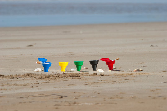 Composizione di posacenere colorati sulla spiaggia, circondati da conchiglie , mare sullo sfondo