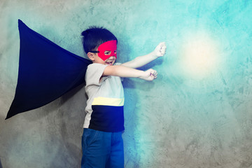 The boy dressed up in a superhero outfit, pretending to fight in studio,has light effect.Boy power concept And development of young children.