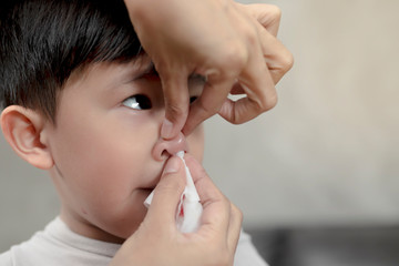 Portrait of cute Asian ethnic child having nosebleed,The concept of first aid for nosebleeds.