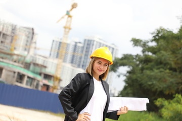 woman Malay Chinese worker engineer management hard safety hat helmet at construction site holding plan look at camera