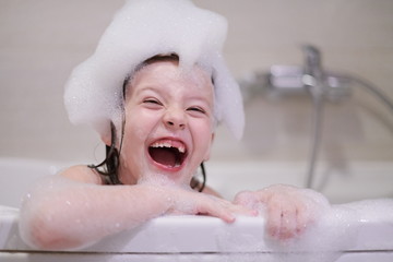 little girl in bath playing with soap foam