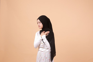 Portrait of Asian Muslim woman wearing a hijab feeling the pain of the background of a headache. Indonesian women