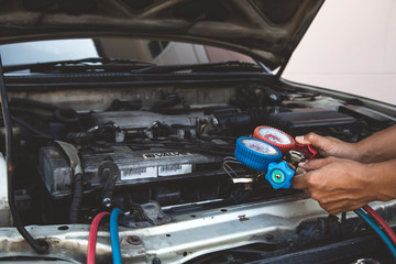 Auto mechanic using measuring equipment for filling car air conditioners checking. Concepts of car Repair service and car insurance.