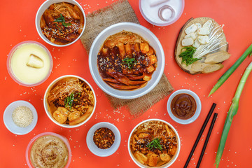 A set of Korean food is served warm on the orange background.