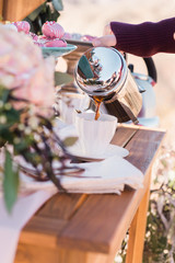 French press coffee maker pouring coffee into romantic style coffee cup outdoors