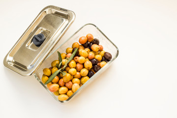 Natural green olives in glass container with metal cover on white background.