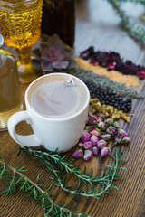 Cup of coffee on wood table with rows of dried flowers, herbs and spices