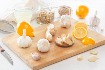 Ginger, garlic, lemon, dried medical chamomile in a jar and ginger tea - a means to protect against viral infections and colds on a light wooden table.