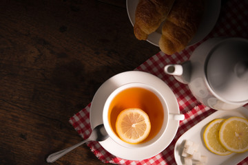 Top view image of a cup of tea with lemon on wooden table