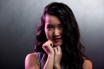 portrait of a beautiful asian woman with gold earrings and red lips being happy and posing in isolated background. she long black hair and smooth clean skin