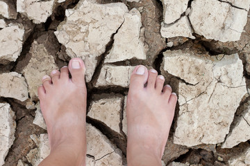 The top view of a woman's feet standing on the ground is dry from dehydration until it breaks.