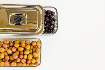 Natural green and black olives in glass container with metal cover on white background.Top view