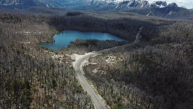 Tilt Up Aerial View of Glacial Lake, Snow Capped Anes Mountain Peaks And Road Between Chile and Argentina