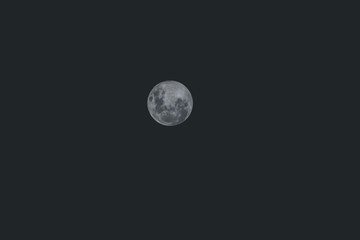 telephoto shot of full super moon in the night sky, with gently faded tones