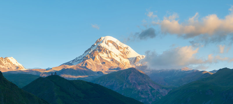 Beautiful sunrise in Stepancminda, Georgia. View to the Kazbek mountain and Trinity church. Banner edition..