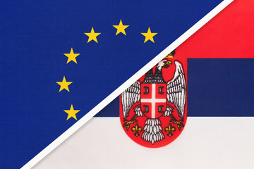 European Union or EU vs Serbia national flag from textile. Symbol of the Council of Europe association.