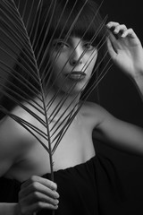 black and white portrait of a young woman with leaf palms.