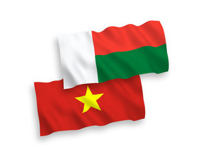 National vector fabric wave flags of Madagascar and Vietnam isolated on white background. 1 to 2 proportion.