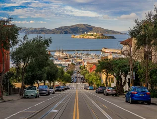 Poster Iconic cable car tracks atop Hyde Street, with the famous Alcatraz Island in background in San Francisco, California USA © SvetlanaSF