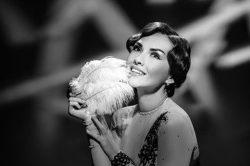 Monochrome portrait of smiling attractive woman posing with retro feather
