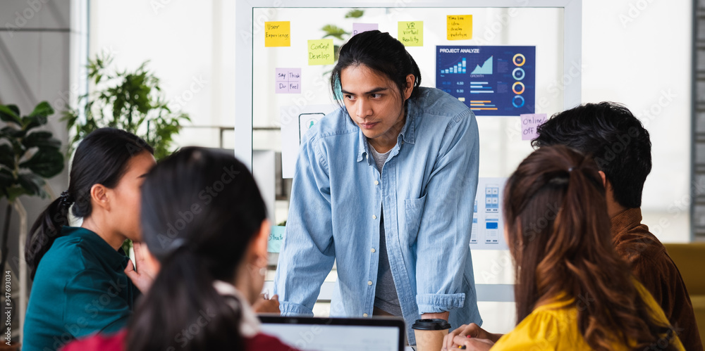Poster asian ux developer and ui designer brainstorming about mobile app interface wireframe design on meeting table with at modern office.Creative digital development agency