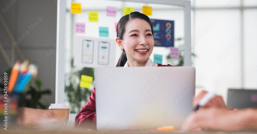 Poster portrait of asian female leader smiling when meeting with ux developer and ui designer about mobile app interface wireframe design on meeting table at modern office.Creative digital development agency