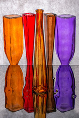 Still life with inverted colored bottles on a reflective surface