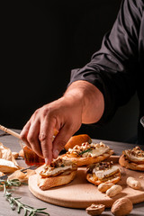 Food recipe background. chef preparing delicious bruschettas with brie camembert cheese, pear nuts and rosemary, New Years Eve or Christmas party appetizer Close up