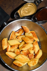 Fried potato dumplings served in a pan with sausages, fried onion, cheese sauce.