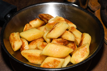 Fried potato dumplings served in a pan with sausages, fried onion, cheese sauce.