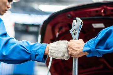 auto mechanic man holding wrench bumping fists with team colleague worker in auto repair shop. concept of teamwork working for car maintenance service industrial. automotive business manufacturing 