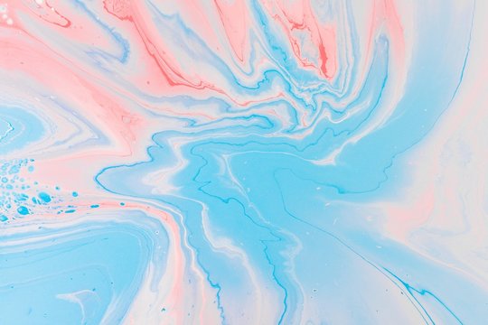 Overhead shot capturing blue, pink and white color splashes, to be used as abstract wallpaper