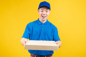 Delivery express of pizzaman asian male showing box delicious fast deliver to receiver shipping buying online order wearing blue uniform on yellow background isolated studio shot.