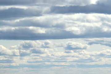 Clouds in the blue sky at sunset or dawn backlit by the sun. Place for text and design.