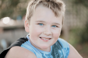 Closely cropped portrait of 9 year old boy smiling with sparkling blue eyes