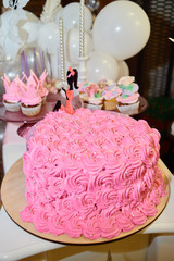 Candy bar served with pink cake, cupcakes, candles and balloons on table, copy space. Dessert table for party. Holiday or birthday concept