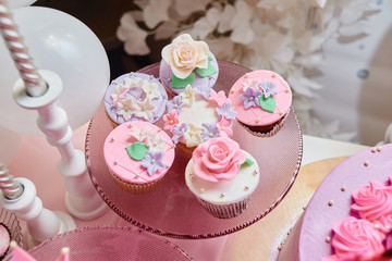 Pink vanilla cupcakes on glass stand, copy space. Dessert table for party. Holiday concept. Candy bar
