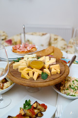 Wood board with assortment of cheese, nuts and honey on dinner table. Cheese plate