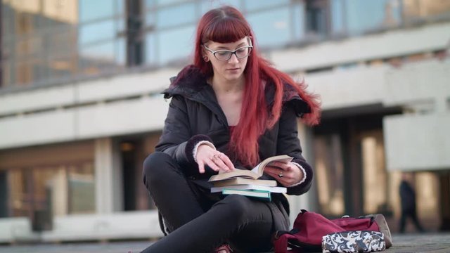 Hipster student can't find the answer she's looking for in book so searching online using her phone.
