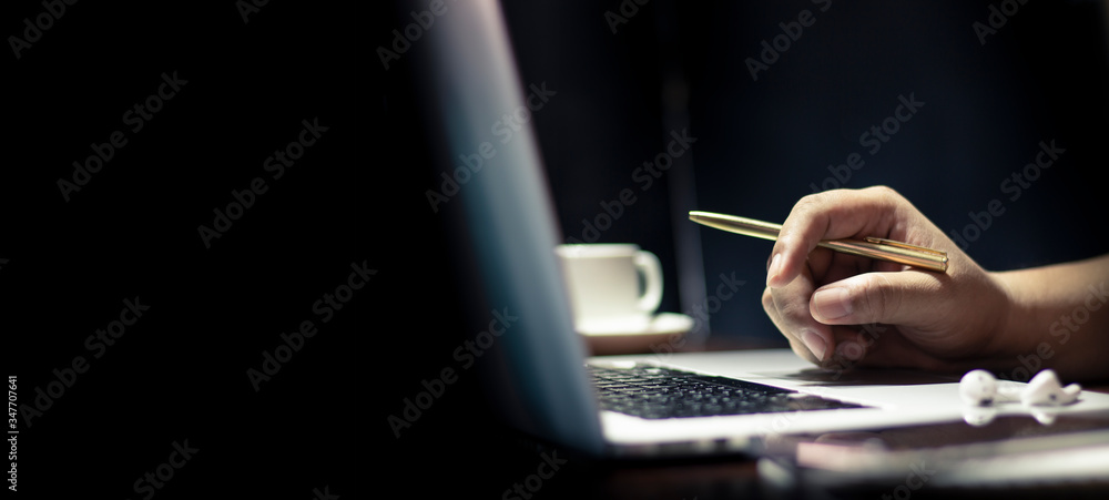 Poster man using laptop or computer working at home in the at night and have glass coffee, book on table. f
