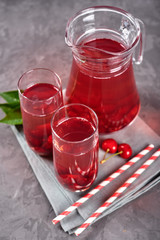 Fresh cherry lemonade in glasses with paper straws and jug on gray table background, copy space. Cold summer drink. Berry cocktail