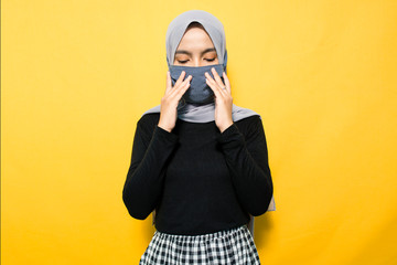 Asian woman wearing mask and holding mouth