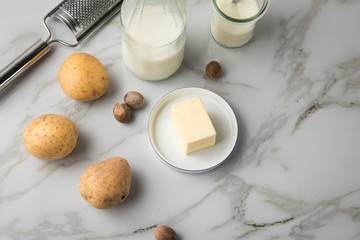 Kartoffeln, Milch, Salz, Butter, Muskatnuss als Zutaten mit Muskatreibe für Kartoffelpüree auf hell Marmor Hintergrund