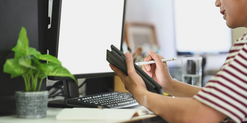 Cropped image of smart man holding a empty screen computer tablet and stylus pen while sitting in...
