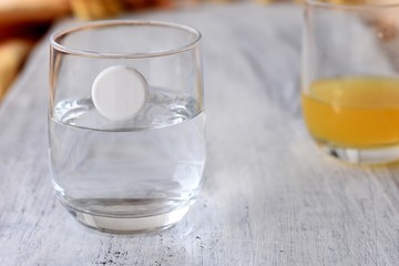 Closeup of effervescent pill falling into glass of water