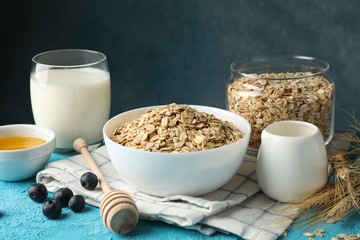 Composition with oatmeal flakes on blue background. Cooking breakfast